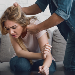 Man pulling woman's hair during a domestic violence incident on a couch.