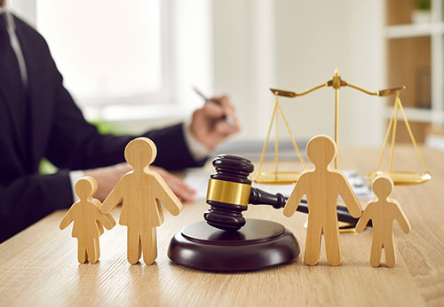 Wooden family figures, a gavel, and scales of justice, representing Texas family law